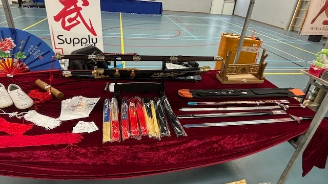 Marktkraam met zwaarden op een rode tafel met verschillende accessoires zoals schoenen en een waaier